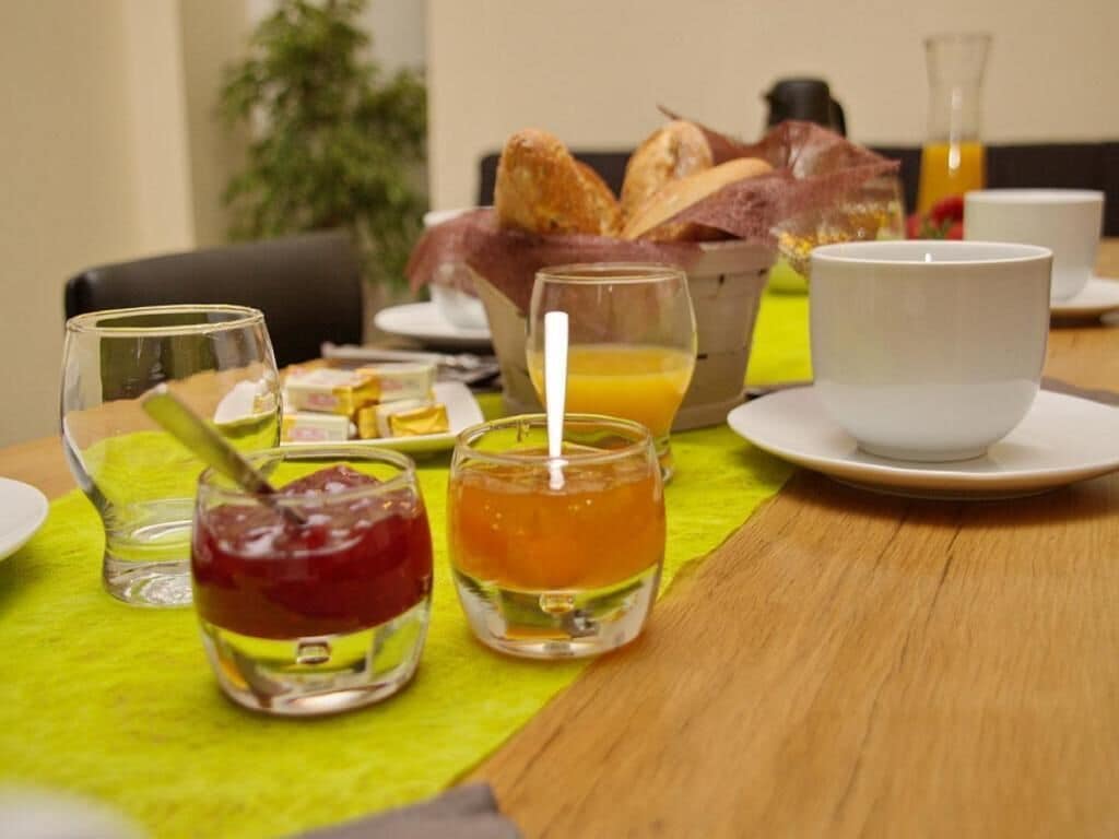 A breakfast setting with a table, a basket of bread, a glass of orange juice, and a cup.