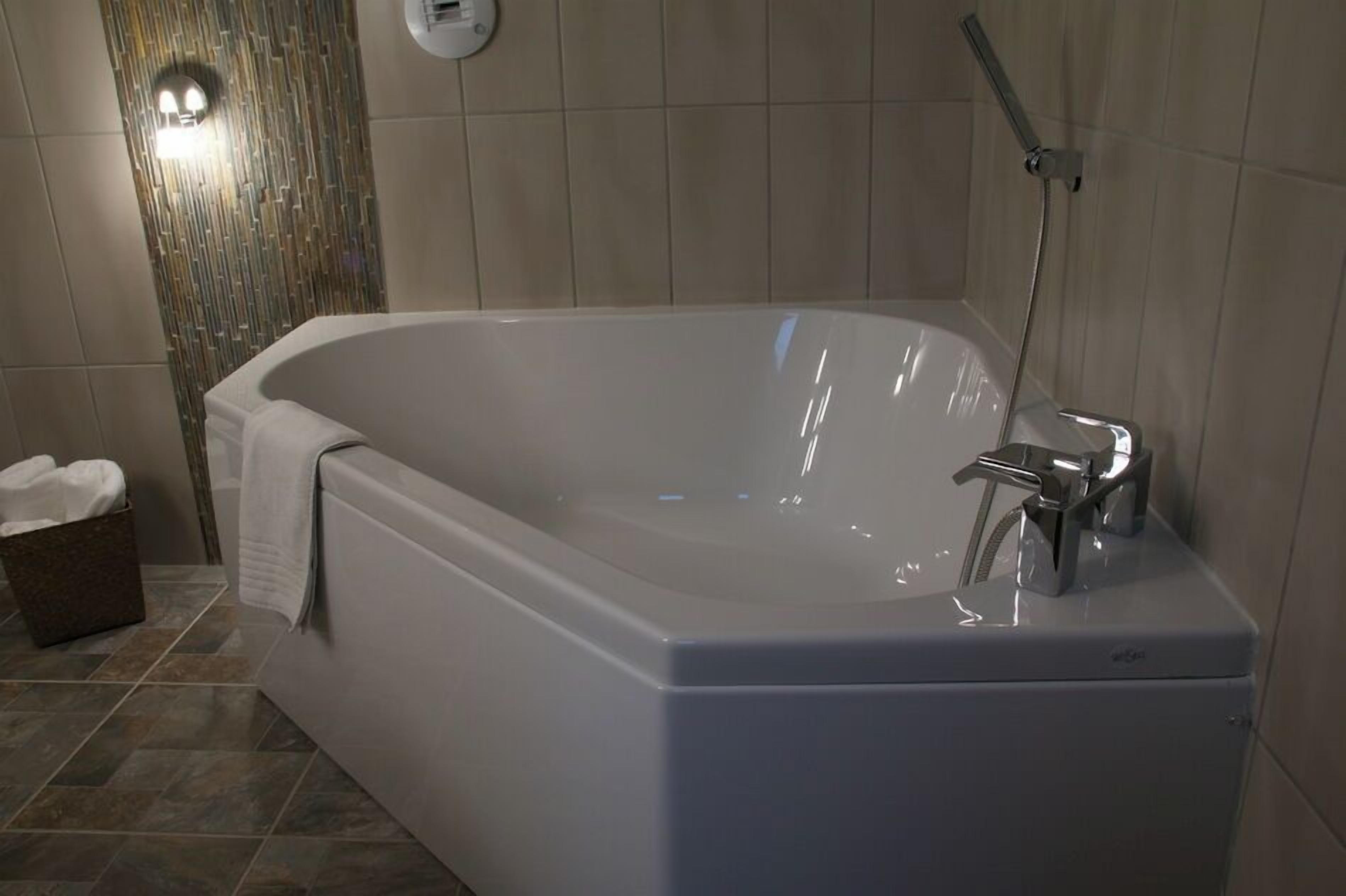 Un baño moderno con una bañera independiente, un cabezal de ducha manual y un perchero para toallas.