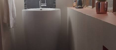 Un baño moderno con un lavamanos independiente, un espejo y una ventana con persianas.