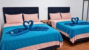 Two twin beds with matching headboards and pink bedding, arranged in a room with wooden flooring. - Pousada Miss Roses (Foz do Iguaçu)