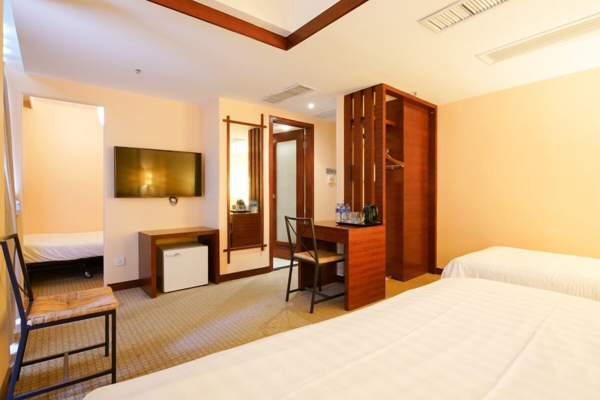 A hotel room with a bed, a desk, a chair, a TV, and a wardrobe.