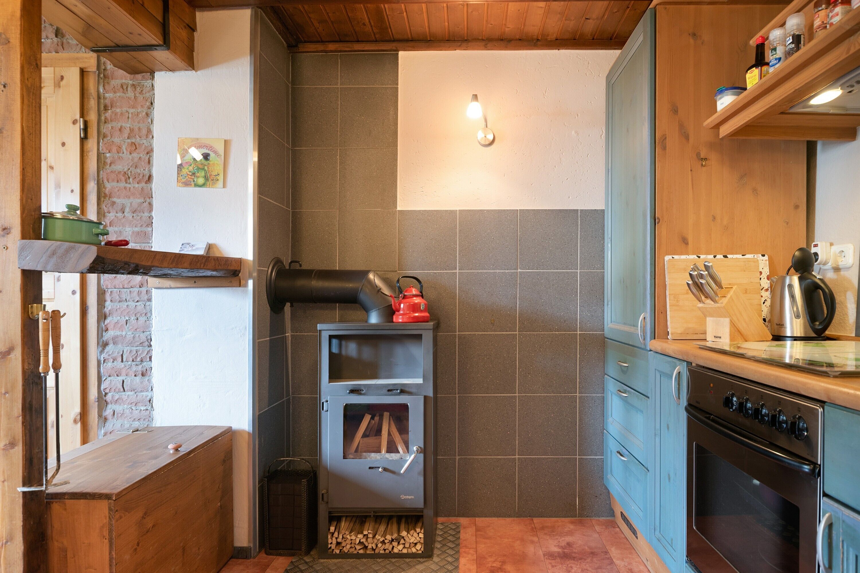 Una cocina con estufa de leña, un lavaplatos y armarios.