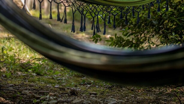 A hammock in a natural setting with a wooden cabin in the background. - Chalet Suite Iris (Saint-Remèze)