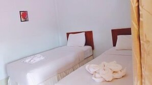 A hotel room with two single beds, a small bedside table, a wall-mounted air conditioner, and a framed picture on the wall. - Orchids Guesthouse (Chiang Rai)