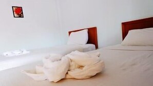 A hotel room with two beds, a wooden headboard, a white wall, and a small picture frame. - Orchids Guesthouse (Chiang Rai)
