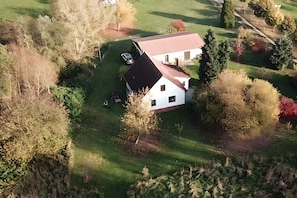 Eine Luftaufnahme eines Hauses mit schrägem Dach, umgeben von einem gepflegten Rasen und Bäumen.