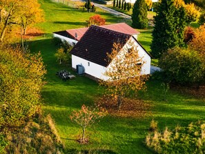 Une maison de plain-pied avec un toit rouge, entourée d’une pelouse bien entretenue et d’arbres.