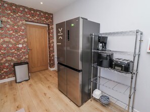 A kitchen with a stainless steel refrigerator, a coffee maker, and a toaster on a wire shelf. - Amber Rose (Berwick-upon-Tweed)