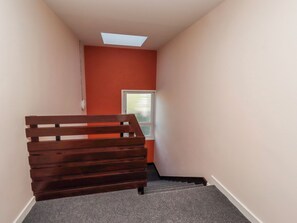 A staircase with a wooden bench at the bottom, a window, and a ceiling light fixture. - Amber Rose (Berwick-upon-Tweed)