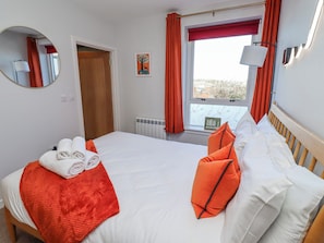 A hotel room with a bed, a window with curtains, a radiator, a mirror, and a wall-mounted picture. - Amber Rose (Berwick-upon-Tweed)