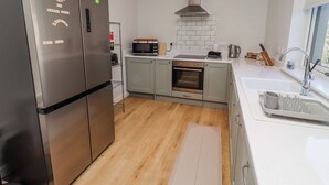 A modern kitchen with stainless steel appliances, a microwave, oven, and a sink. - Amber Rose (Berwick-upon-Tweed)