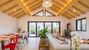 A spacious living area with a high ceiling, a sofa set, a dining table with chairs, and a large window providing a view of the outside. - Le Balzac – Architect-designed home 132m² (Dijon)