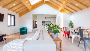 A modern loft-style living space with a high ceiling, a dining area, and a kitchen visible through an open doorway. - Le Balzac – Architect-designed home 132m² (Dijon)