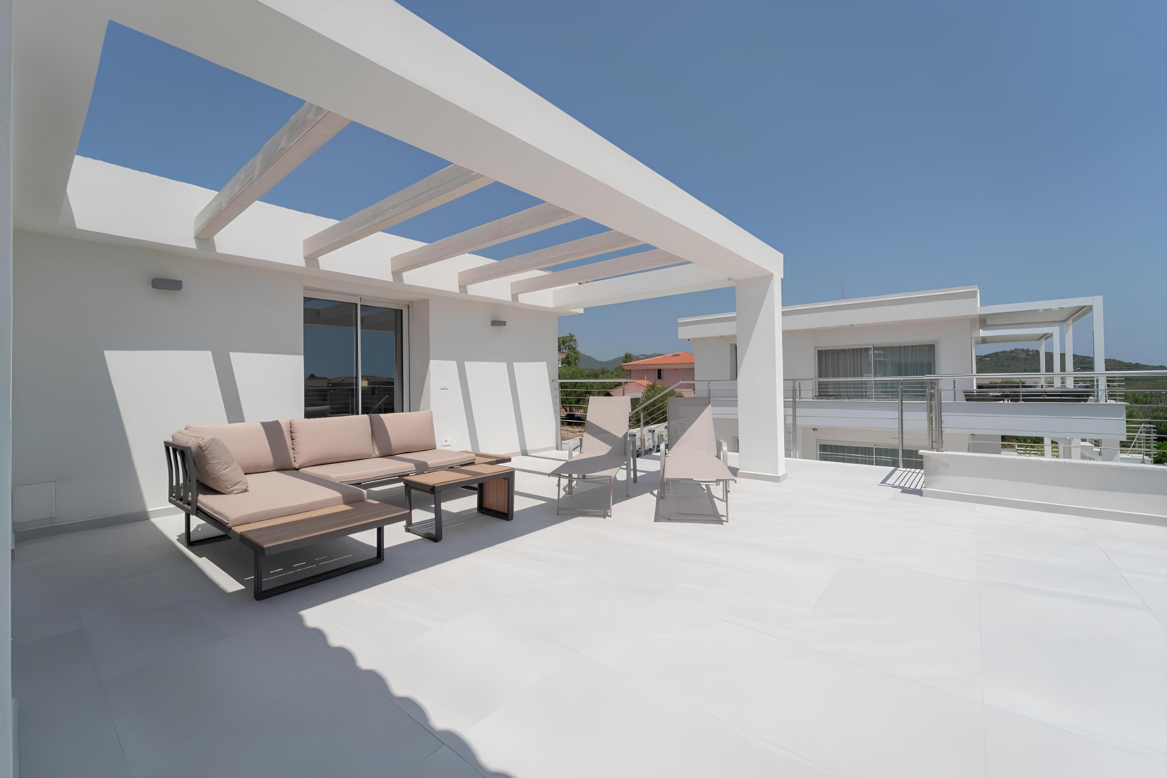 Un espace de vie extérieur moderne, comprenant un canapé, des fauteuils et une table.