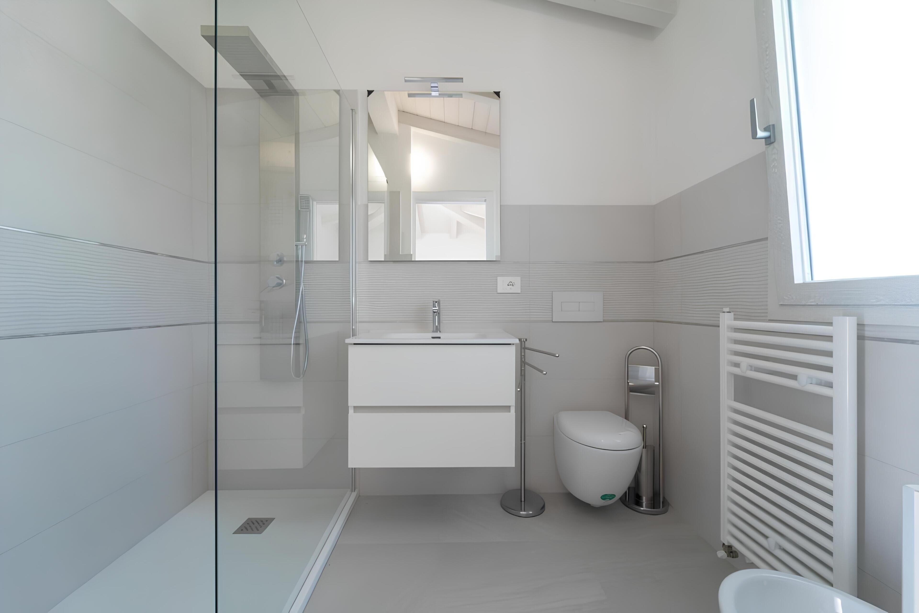 A modern bathroom with a glass shower enclosure, a white sink, a toilet, and a towel rack.