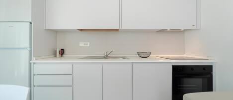 A modern kitchen with white cabinetry, a built-in oven, and a sink.