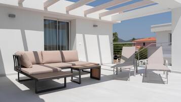 A modern outdoor patio with a sofa, a table, and chairs.
