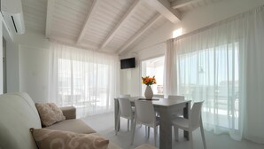 Una sala moderna con un sofá, una mesa de comedor, sillas y un televisor.