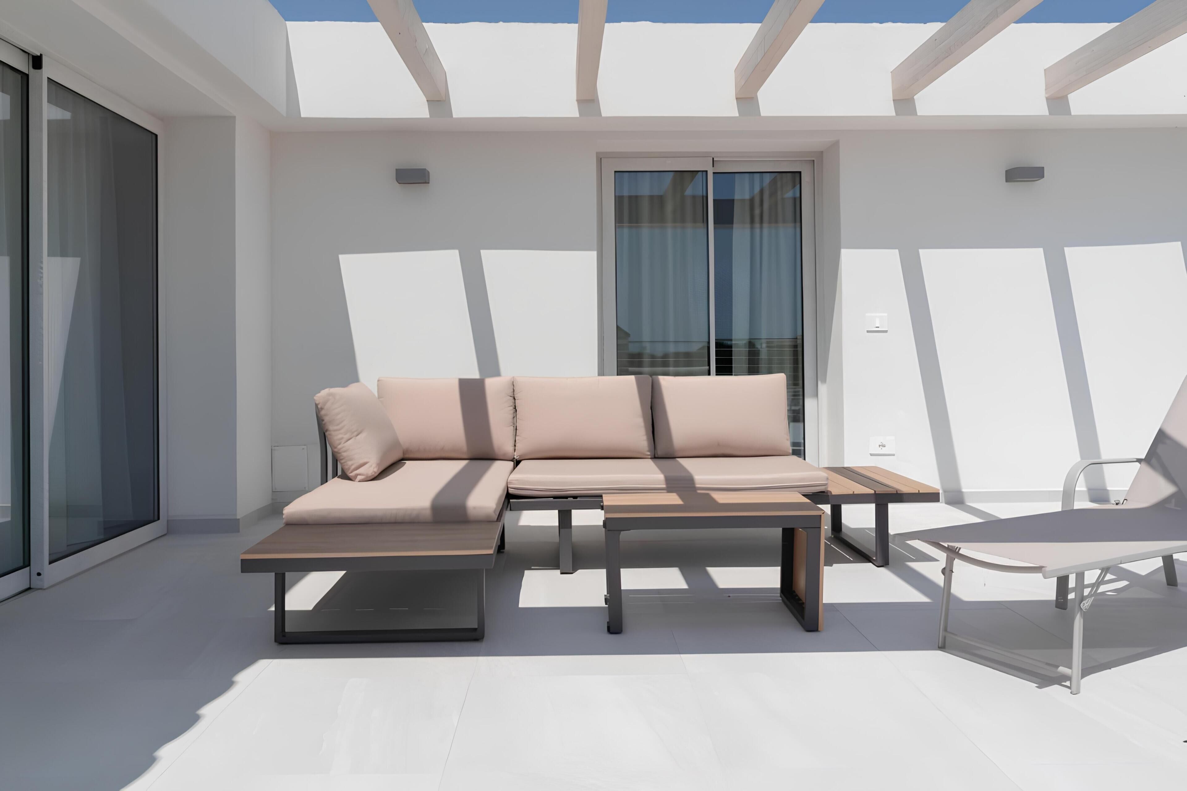 A modern outdoor living area with a sofa, a table, and a chair.