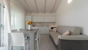 Una cocina moderna con armarios blancos, una mesa de comedor con sillas y un sofá.