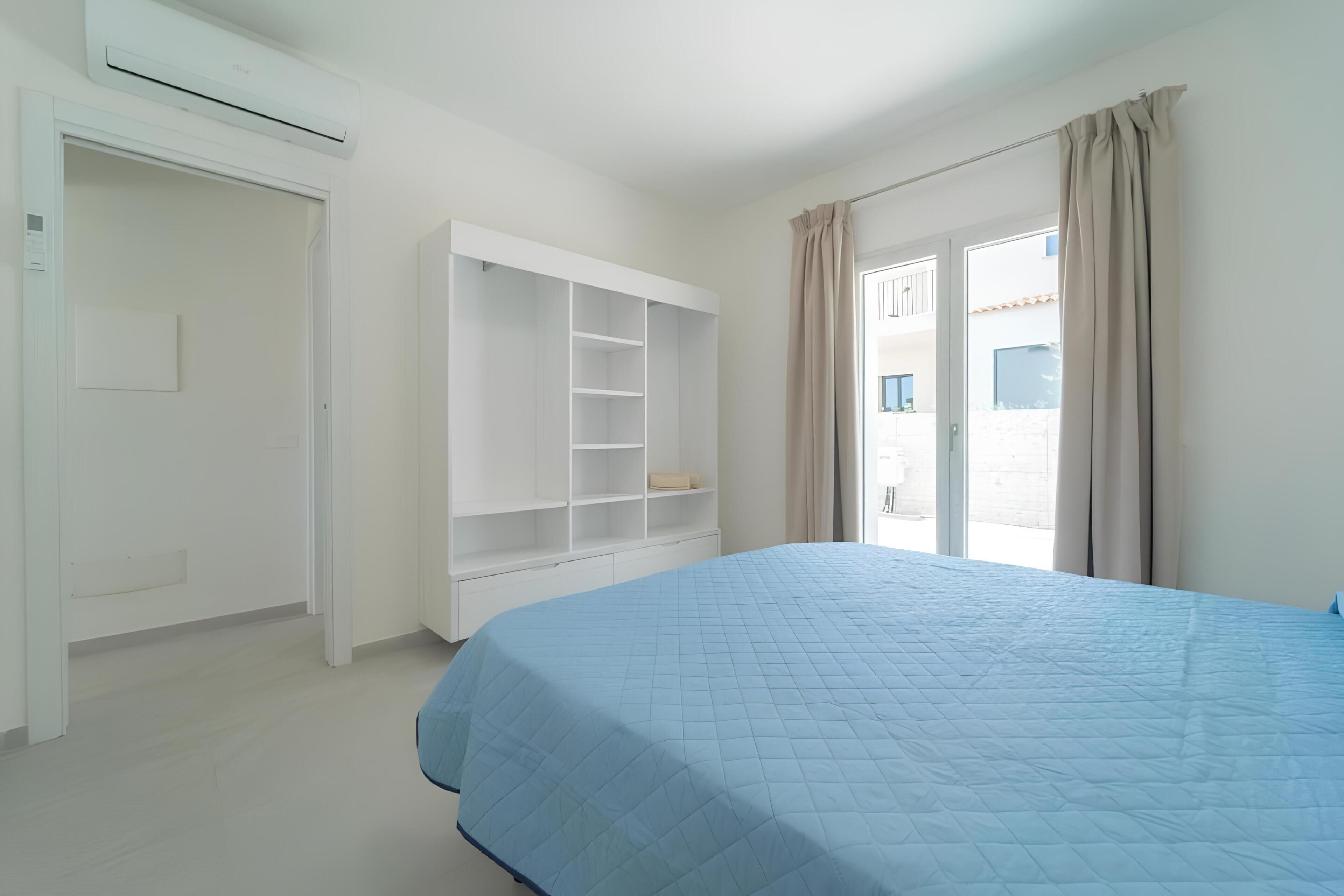 A bedroom with a bed, a wardrobe, and a window with curtains.