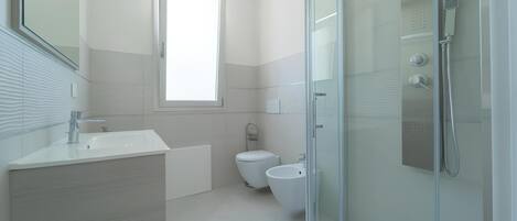 A modern bathroom with a glass shower enclosure, a toilet, and a sink.