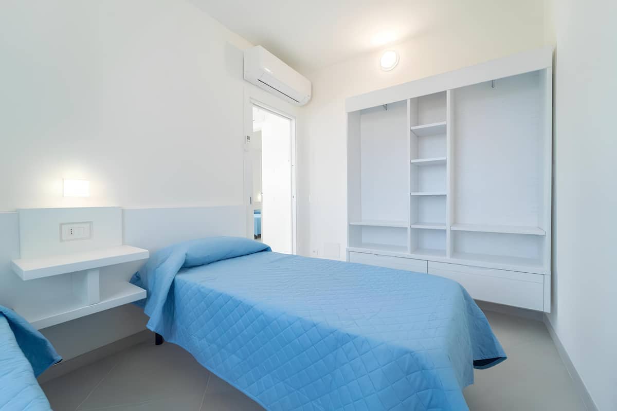 Un dormitorio con cama, mesita de noche, armario y equipo de aire acondicionado.