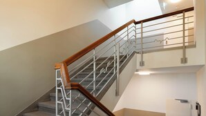 Una escalera con barandilla de madera y pasamanos metálicos que conduce a un piso superior.