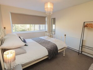 A bedroom with a bed, a window, a radiator, and a chandelier. - Coastal Retreat (Scarborough)