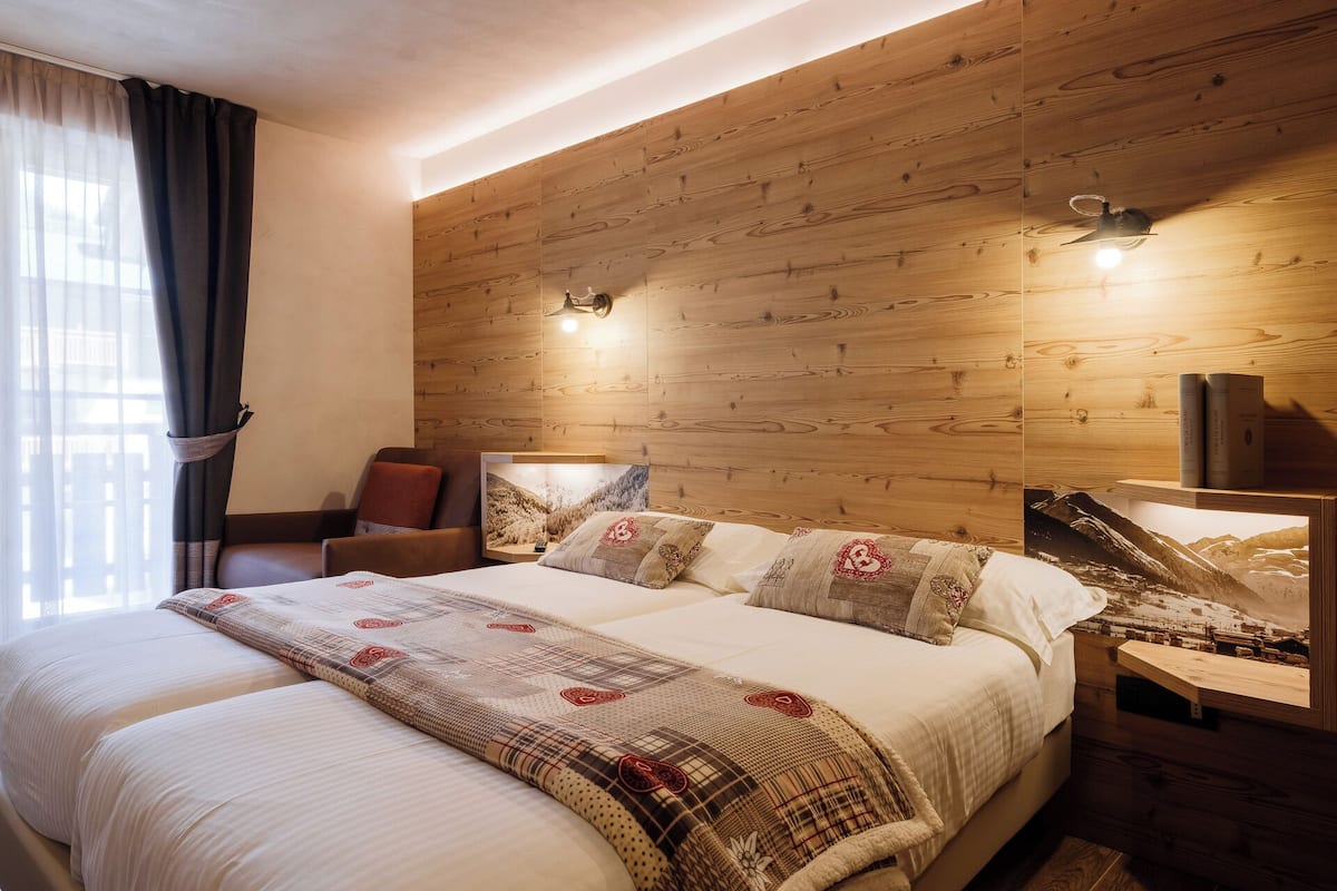 A bedroom with a wooden headboard, a bed with patterned bedding, a nightstand, and a bookshelf.