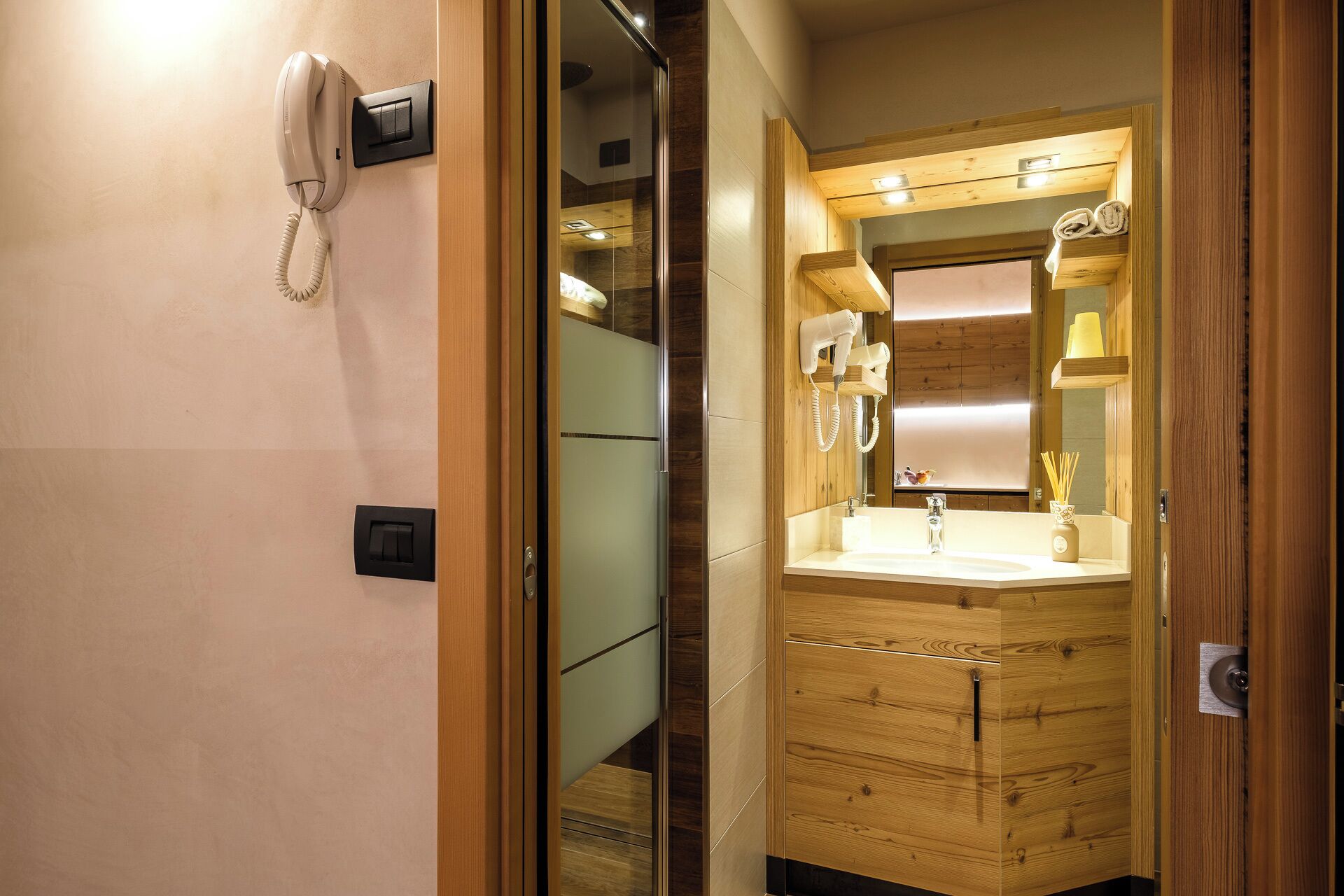 Een hotelbadkamer met een houten wastafel, een spiegel, een wasbak en een haardroger.