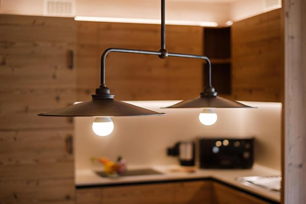 Ett kök med träskåp, en hängande lampa och en kaffemaskin.