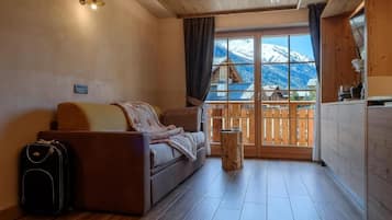 Una habitación acogedora con un sofá, una mesita y una ventana con vistas a montañas.