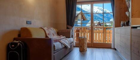Una habitación acogedora con un sofá, una mesita y una ventana con vistas a montañas.