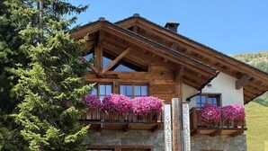 Un edificio de estilo chalé con paredes de piedra, balcones de madera y vistas despejadas del paisaje circundante.