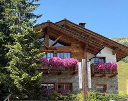 Un edificio de estilo chalé con paredes de piedra, balcones de madera y vistas despejadas del paisaje circundante.