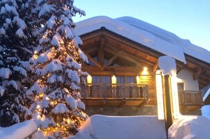 Un edificio cubierto de nieve con un balcón de madera y un árbol de Navidad iluminado.