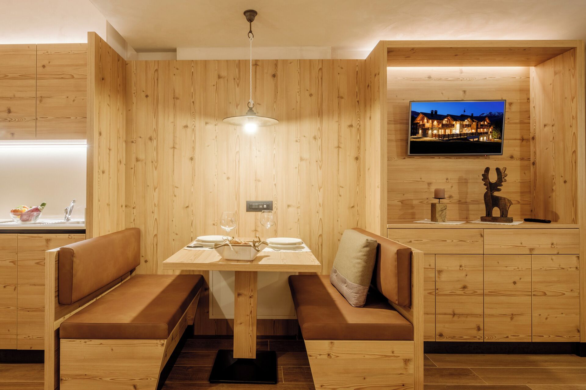 Un interior de madera con una mesa de comedor, bancos, un televisor y una chimenea.