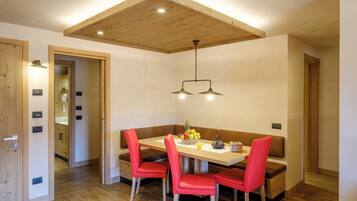 Een eetruimte met een houten plafond, een bank en rode stoelen.