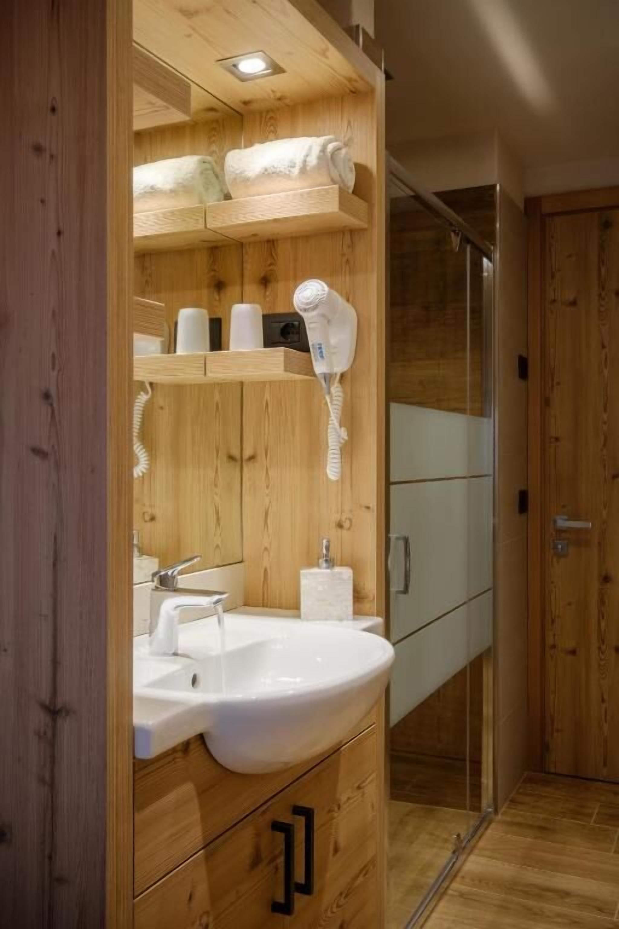 A wooden bathroom with a sink, mirror, and towel rack.