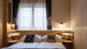 Un dormitorio con una cama, dos mesitas de noche, un ventanal con cortinas translúcidas, una lámpara de pared y un cartel en la pared.