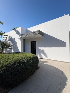 Un edificio moderno con techo plano, un muro de piedra decorativo y una siega de seto bien cuidada.