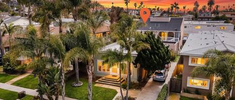 A residential area with houses, palm trees, and a sunset sky.