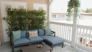 Ein Balkon mit einem blauen Sofa, einem Holztisch und einem Blumentopf.
