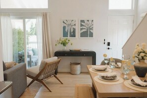 A dining area with a table set for two, a sofa, and a chair. There are two framed pictures on the wall above the table. - OB Townhome, 2 blocks to beach with Private Garage (San Diego)