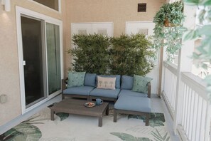 Ein Balkon mit einer Couch, einem Couchtisch und Topfpflanzen.