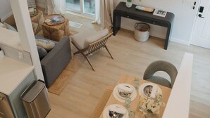 Ein modernes Wohnzimmer mit Essbereich, Sofa und an der Wand montiertem Fernseher.