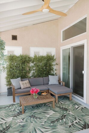 A covered outdoor seating area with a sofa, a coffee table, and a potted plant. - Heart of OB, Walk to Beach, Townhome with Garage and Patio (San Diego)