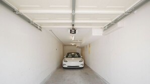 Un auto estacionado en un garaje con una lámpara en el techo y una puerta de garaje.