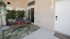 Un patio techado con sofá, una mesa de centro y una planta en maceta.